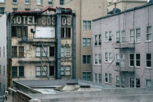 A vintage cityscape showing an old, weathered hotel building with fire escapes and urban details.
