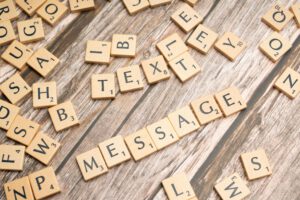 Scrabble tiles spelling 'text message' on a wooden background, ideal for communication themes.