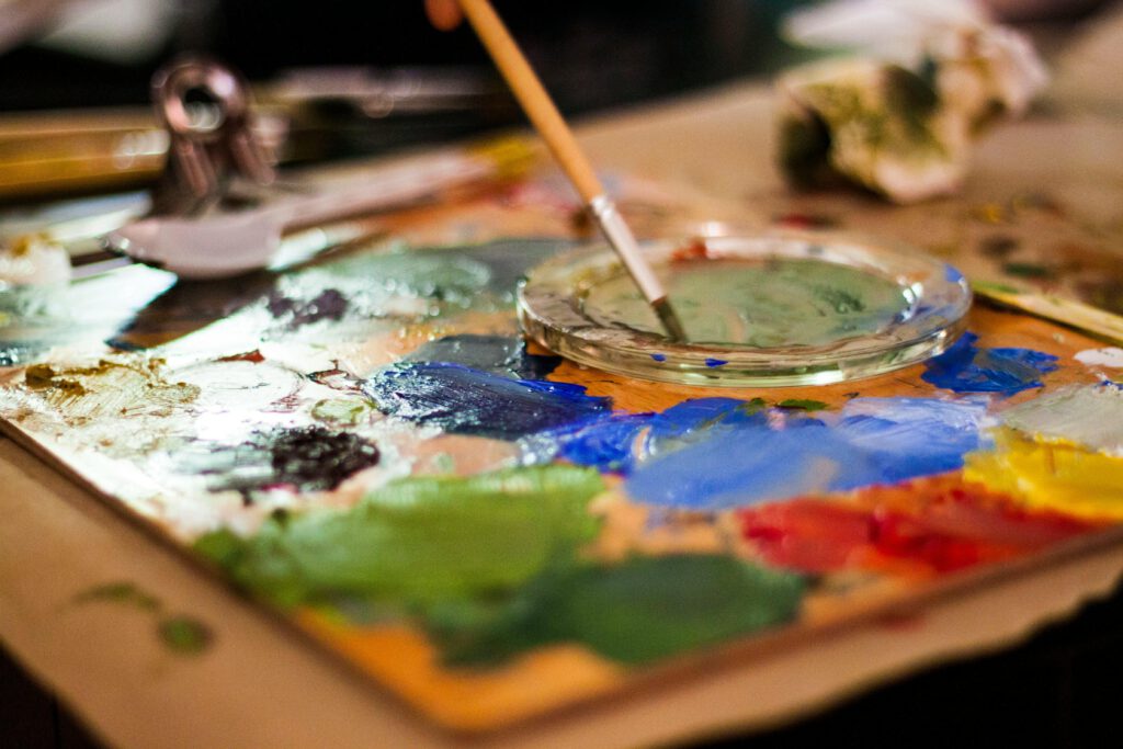 Creative close-up of an artist's palette with vibrant colors and a paintbrush indoors.