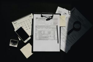 Flat lay of tax documents, calendar, and smartphone on a dark surface, symbolizing tax preparation.