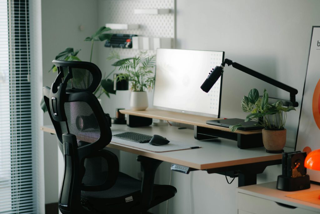 Stylish home office setup with ergonomic chair, plants, and modern desk accessories.