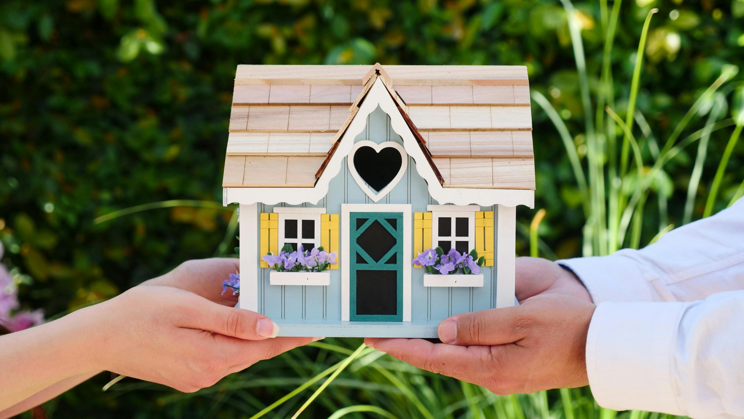 Close-up of hands holding a detailed miniature house model, symbolizing goals of homeownership.