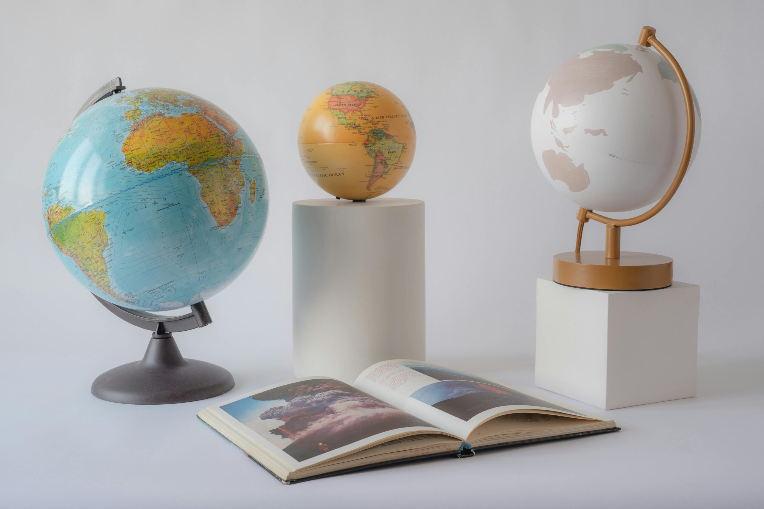 Three globes and an open book on display, perfect for educational themes.